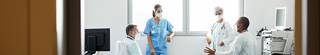 Group of doctors and nurses talking in hospital room.