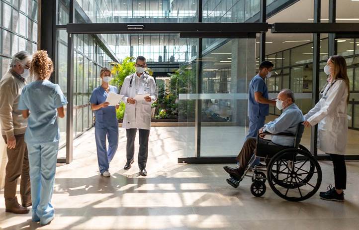 Nurses, doctors, and patients walking through a hospital lobby.