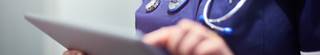 Close-up view of a doctors hand using a tablet device.