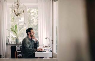 Businessman working at home in casual clothes using his home desktop computer.