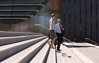 Two business owners walking down a column of stairs together.