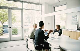 Business professionals sitting at a desk discussing with one another.