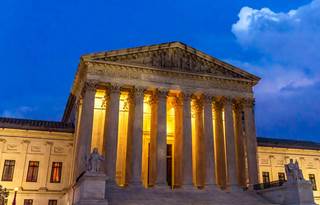 Supreme Court building of the United States featured at night time