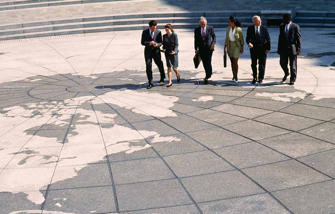 Group of business colleagues walking on a globe designed pavement.
